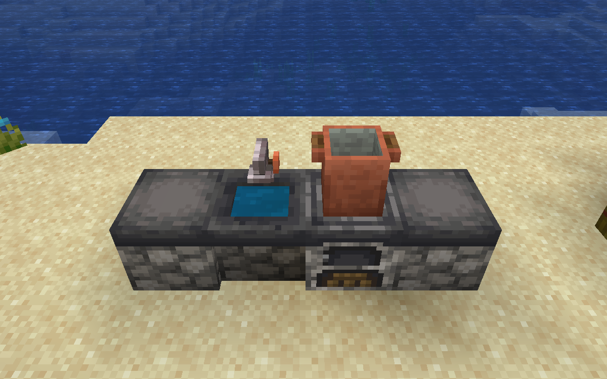 A Candlelight kitchen sink full of water between counters, beside a stove with a cooking pot